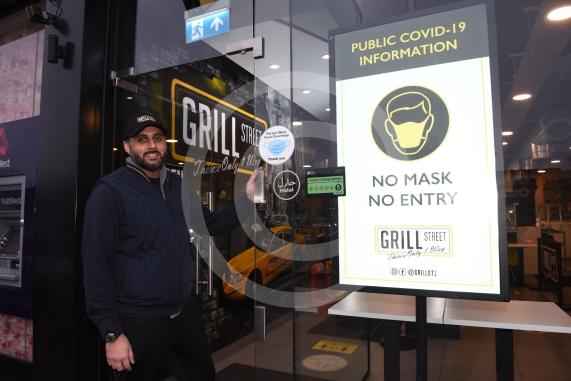 Grill Street owner Bilal Malik , has put up electronic awareness raising signs for COVID-19. Grill Street, 232 Farnham Rd, Slough 
